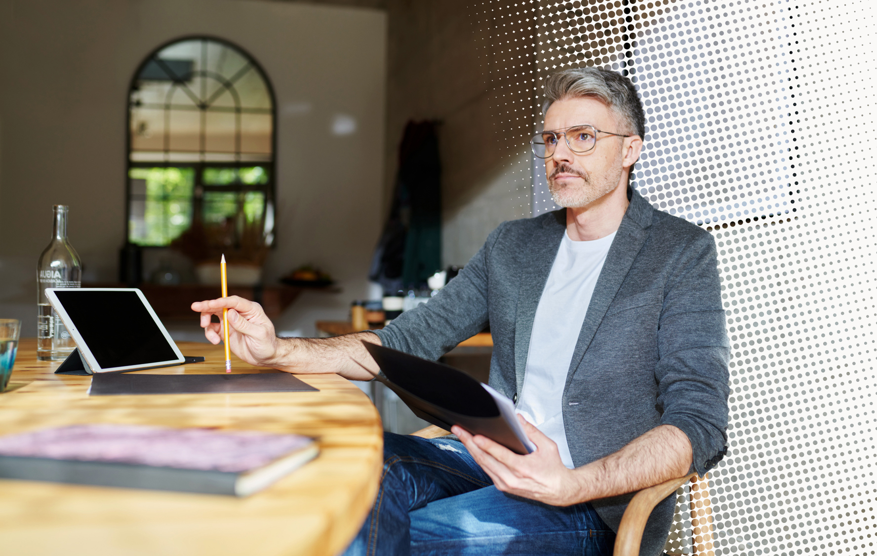 An executive reviews documents beside a tablet at a round wooden table